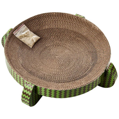 The Spot Nest Cat Scratcher by Spot is a round cardboard scratcher with green zigzag sides, designed to support nail health. It includes a catnip packet on the surface and stands on four short legs.