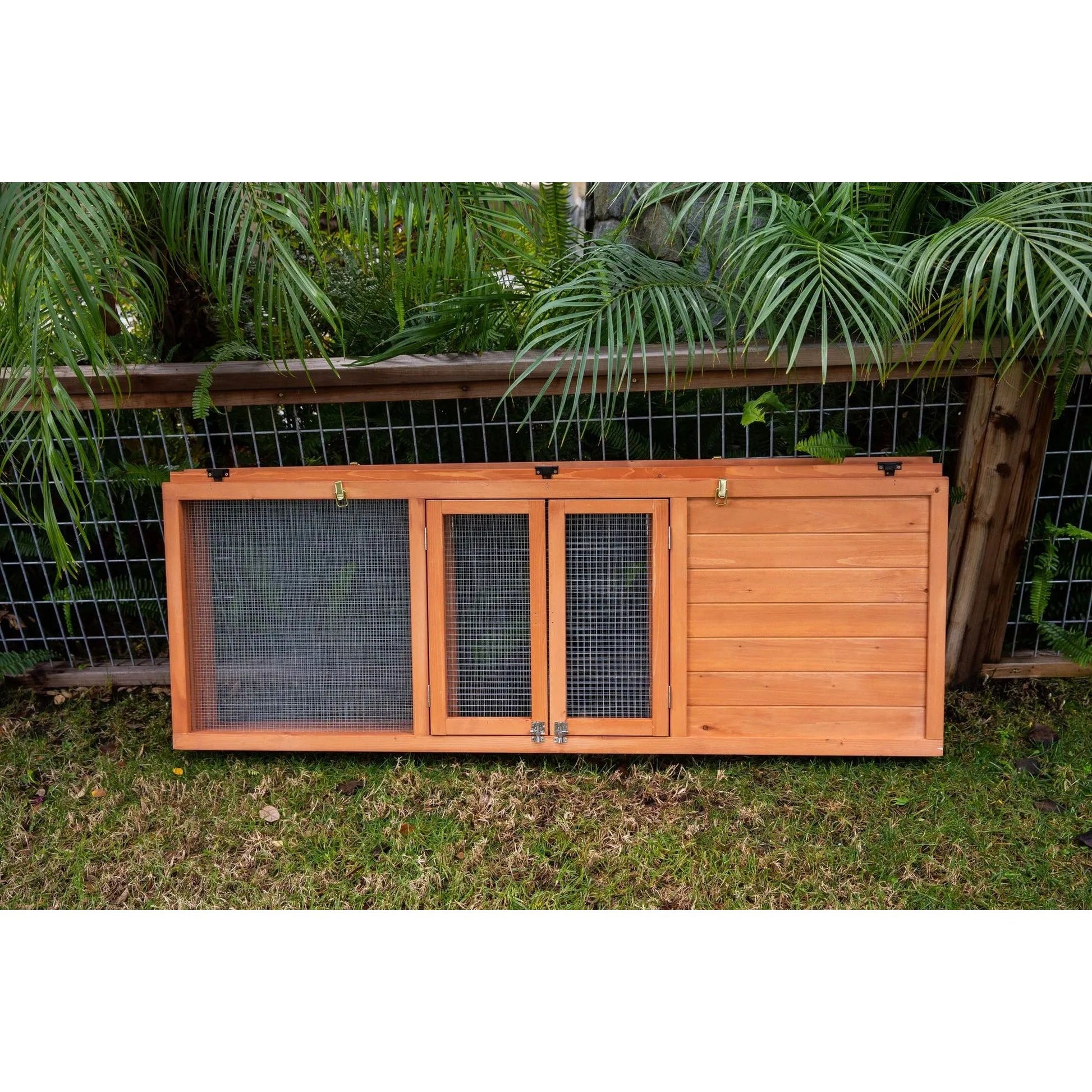 A Zoo Med Laboratories Easy-Fold Tortoise Terrarium Yard door with mesh panels sits on grass—perfect for outdoor tortoise enclosures—set before a wire fence and green plants.