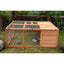 A Zoo Med Laboratories Easy-Fold Tortoise Terrarium Yard with wire mesh sides sits on grass, housing a tortoise and water dish. Green plants and a wooden fence are in the background.