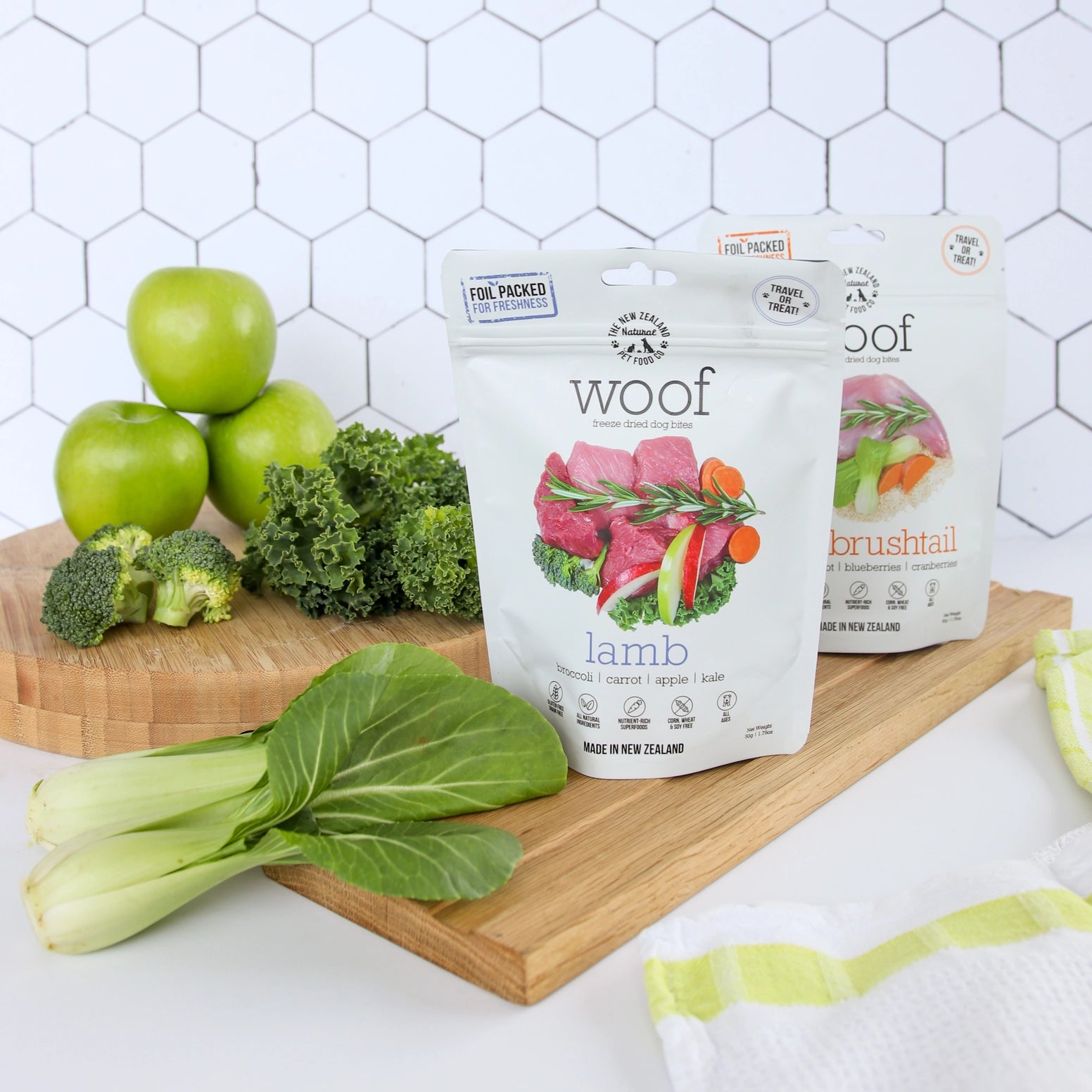Woof lamb freeze dried dog food packaging surrounded by fresh vegetables on a wooden cutting board