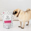 Pug dog sniffing a bag of lamb green tripe dog food topper by The New Zealand Natural Pet Food Co