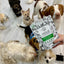 New Zealand green mussel dog treats package held among excited dogs in a pet-friendly setting