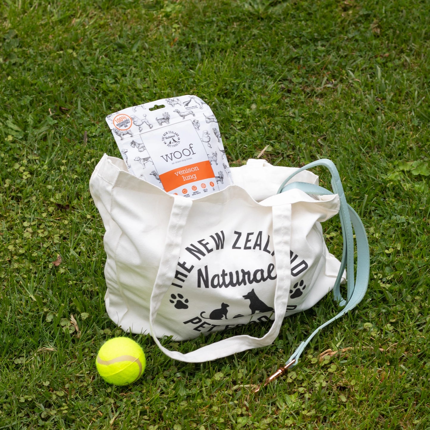 The New Zealand Natural Pet Food Co venison lung dog treats in a bag with a tennis ball on the grass