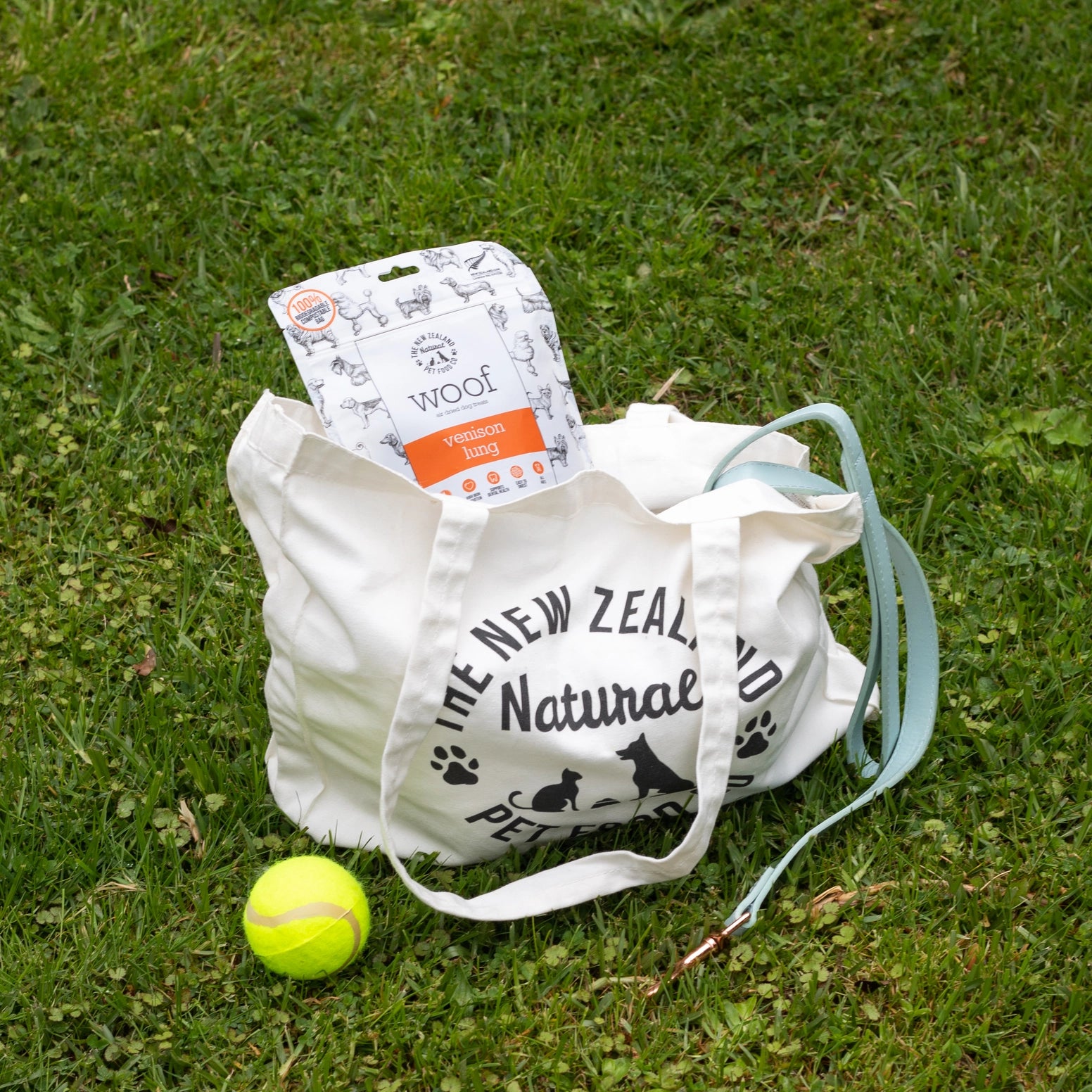 The New Zealand Natural Pet Food Co venison lung dog treats in a bag with a tennis ball on the grass